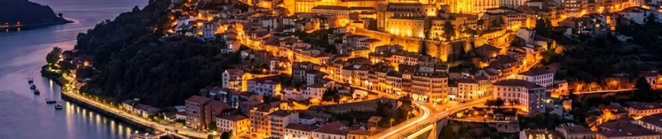 Hilltop city with illuminated buildings and bridge over river at dusk