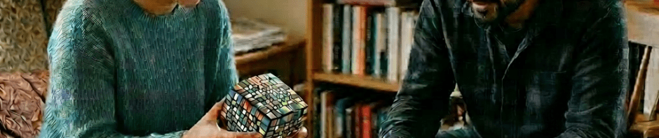 Man and woman playing a board game and holding a large Rubik's cube indoors